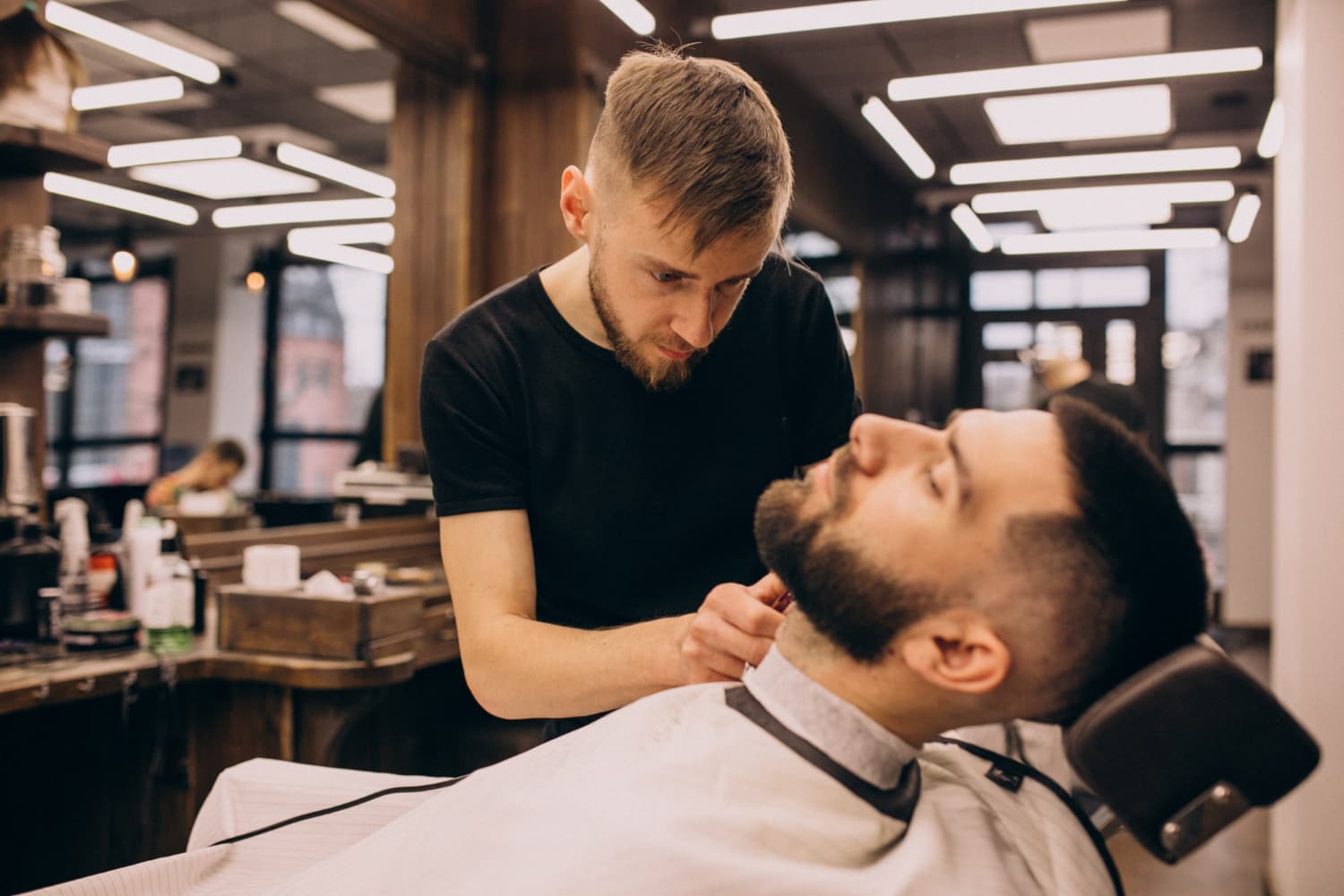 A barber carefully shaping a client’s beard in a Berlin salon